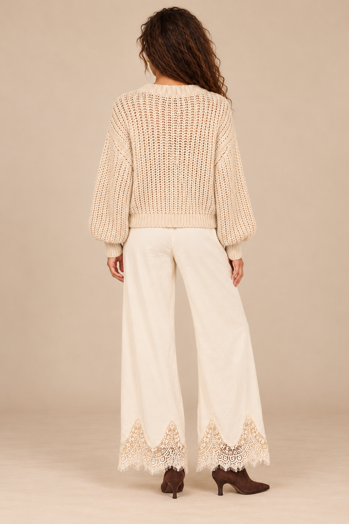 Julia Knit Sweater in Ivory — back view on curly-haired holiday campaign model, cream lace trousers and chocolate boots, light tan studio.