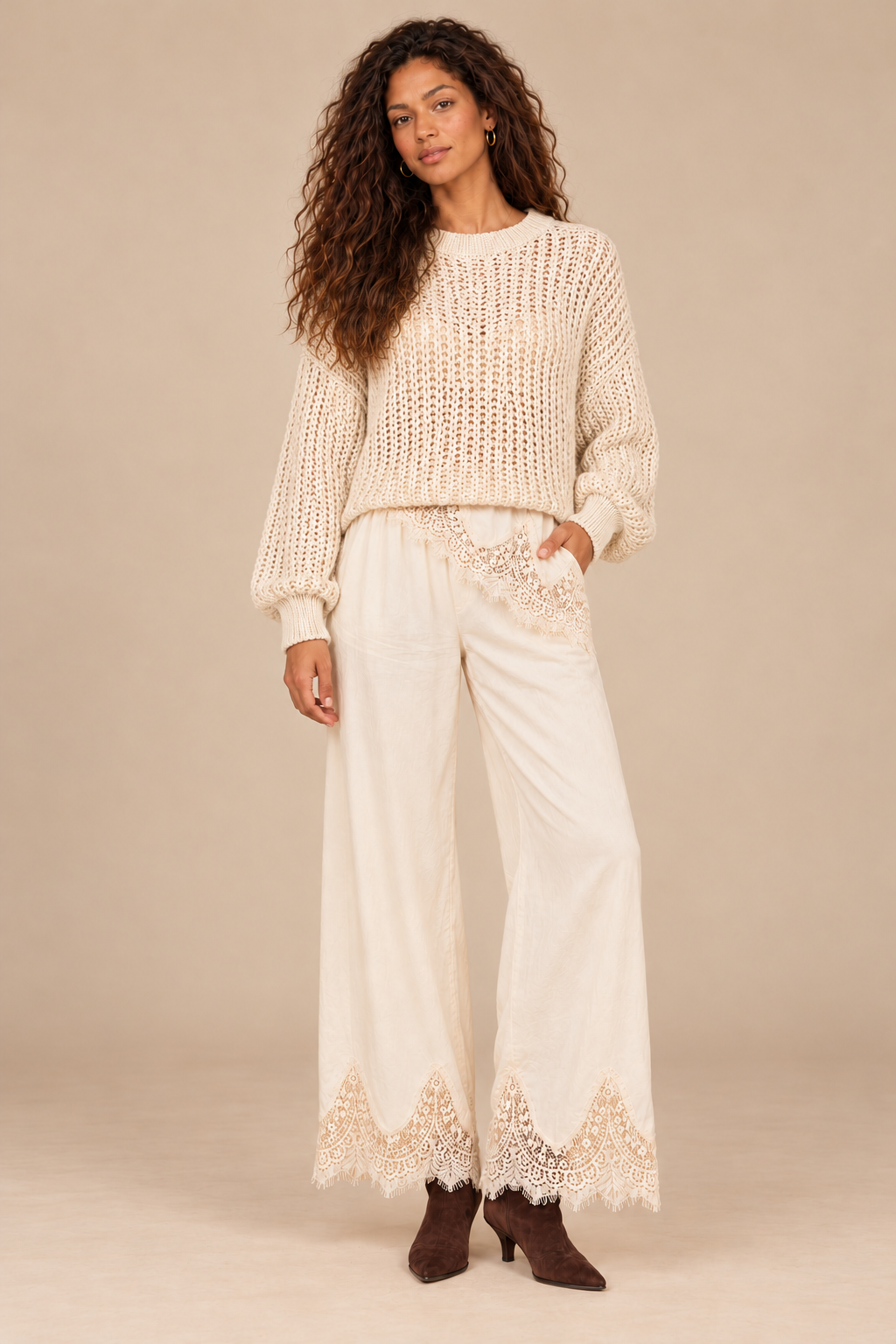 Julia Knit Sweater in Ivory — front view on curly-haired holiday campaign model, cream lace trousers and chocolate boots, light tan studio.