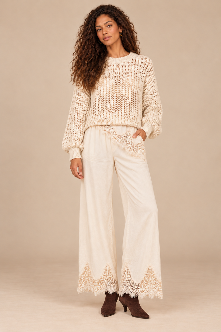 Julia Knit Sweater in Ivory — front view on curly-haired holiday campaign model, cream lace trousers and chocolate boots, light tan studio.