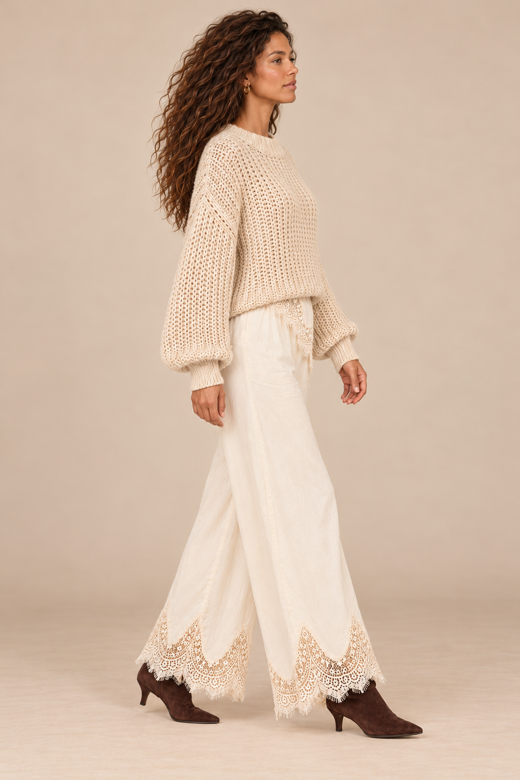 Julia Knit Sweater in Ivory — side view on curly-haired holiday campaign model, cream lace trousers and chocolate boots, light tan studio.