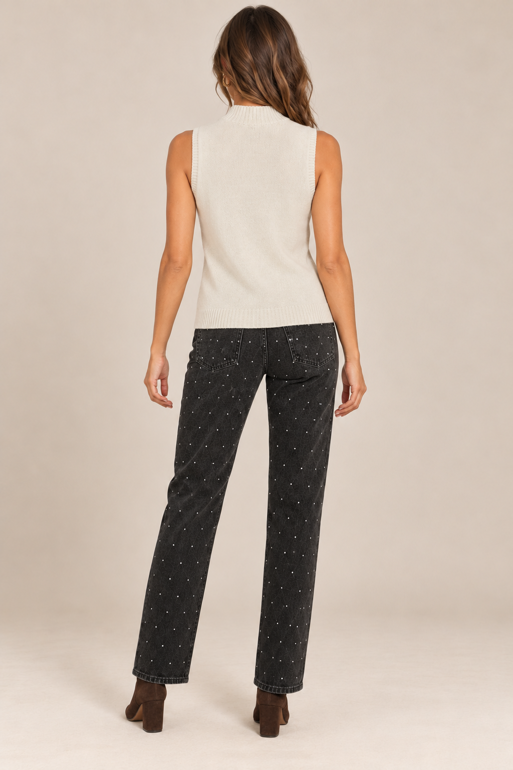 Sleeveless Knit Mock Neck Top in Beige — back view on holiday campaign model, rhinestone black jeans and chocolate boots, light tan studio.