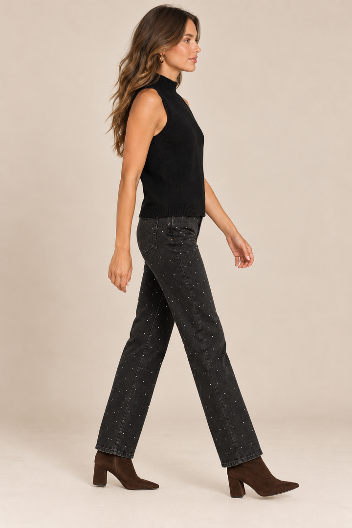 Sleeveless Knit Mock Neck Top in Black — side view on holiday campaign model, rhinestone black jeans and chocolate boots, light tan studio.