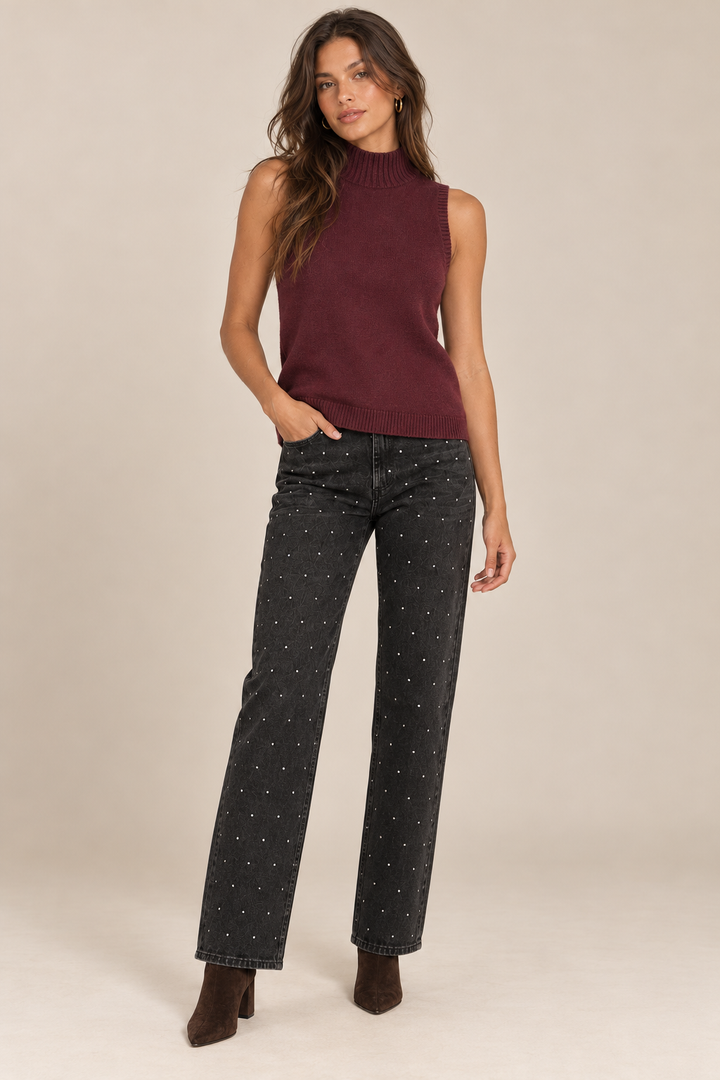 Sleeveless Knit Mock Neck Top in Wine — front view on holiday model, rhinestone black jeans and chocolate boots. Light tan studio background.